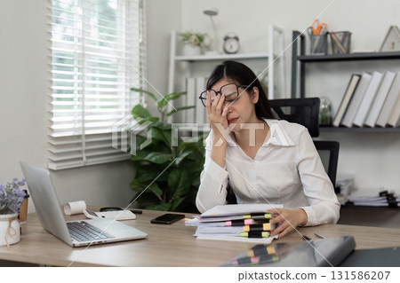 Stressed accountant overwhelmed by paperwork in a modern office setting. Stressed accountant overwhelmed by paperwork in a modern office setting. 131586207