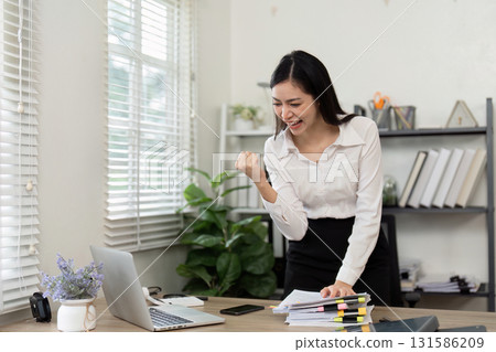 Excited accountant celebrating achievements in a bright office space. 131586209