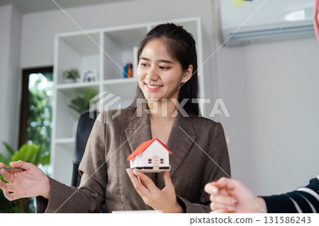 Real estate agent showcasing a model house while discussing property options with a client. 131586243