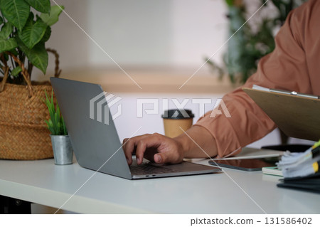 Remote Work. Professional man using laptop for productivity in modern workspace. Remote Work. Professional man using laptop for productivity in modern workspace. 131586402