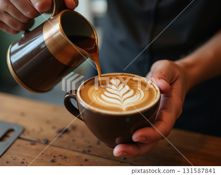 Barista's hands meticulously pouring steamed milk from a copper pitcher to finish a beautiful latte art design. 131587841