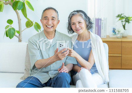 Senior couple looking at a smartphone in the living room Senior couple looking at a smartphone in the living room 131588705
