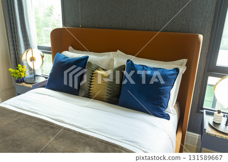Interior view of modern bedroom with blue and yellow pillow on bed. 131589667