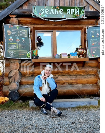 Stylish Woman Sitting in Front of Wooden Cabin Stylish Woman Sitting in Front of Wooden Cabin 131590634
