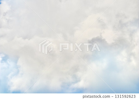 A detailed, closeup view of dense, towering cumulonimbus clouds, showing various shades of white and grey, suggesting heavy weather and dramatic atmospheric depth. 131592623