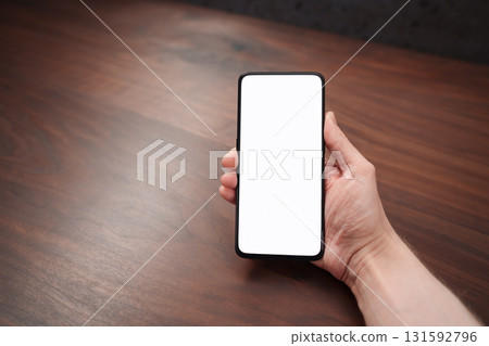 Man hand hold phone with white screen over black walnut table background 131592796