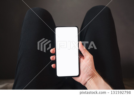 pov shot of man hand hold phone with white screen in dark interior 131592798