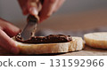 man spreading chocolate nut spread on ciabatta slice on olive board 131592966
