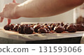 young woman rolling chocolate truffles in cocoa powder on home kictchen 131593066
