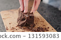 female hands breaking big dark chocolate block with knife on wood board 131593083