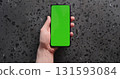Top view man hand show smartphone with green screen on concrete background 131593084