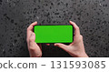 Top view man hand show smartphone with green screen on concrete background 131593085