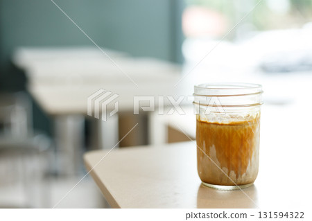 Cup of chilled milk dirty coffee on table by the window. Selective focus. Cup of chilled milk dirty coffee on table by the window. Selective focus. 131594322