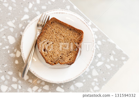 Moist Peanut butter Banana bread sliced with sauce on ceramic plate by the window. 131594332