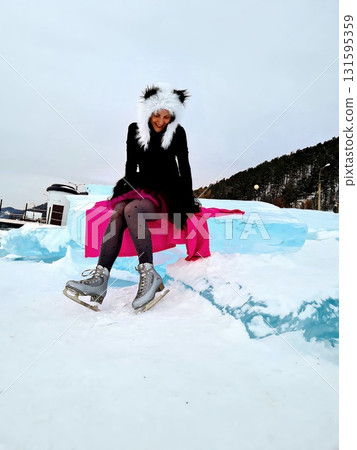 Woman Sitting on Blue Ice Block Wearing Skates 131595359