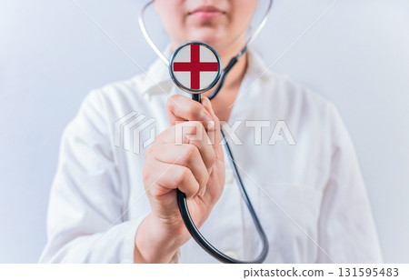 Female doctor holding stethoscope with England flag. National health system of England 131595483