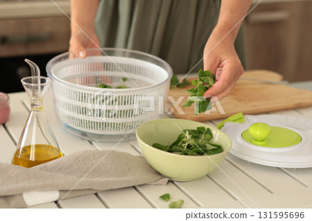 Woman put dried valerian leaves into bowl from dryer. Healthy eating and foods. Mediterranean diet.  131595696