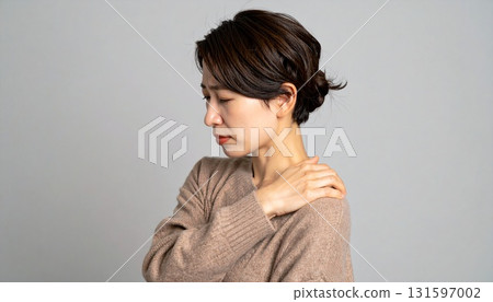 A woman holding her shoulders in a poor health pose A woman holding her shoulders in a poor health pose 131597002