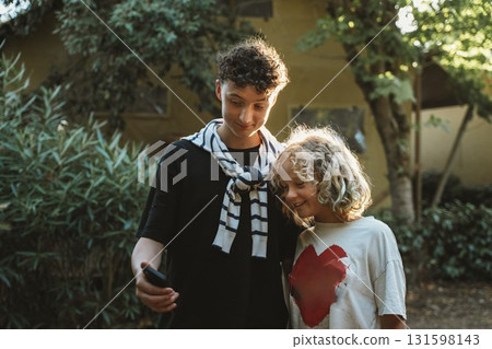 Siblings Smiling and Taking a Selfie with Smartphone 131598143