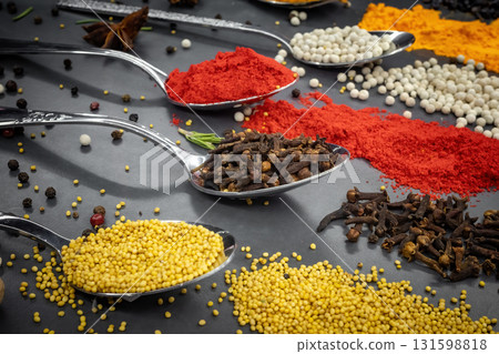 Collection of spices are spread out on a table. The spices include cumin, paprika, and turmeric 131598818