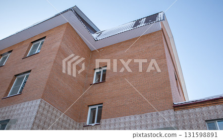 Brick residential building with tiled roof and snow, blue sky, horizontal low angle, worm eye view, low angle Brick residential building with tiled roof and snow, blue sky, horizontal low angle, worm eye view, low angle 131598891