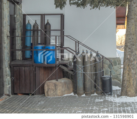 Industrial background, chains, metal cylinders and blue containers by stone wall Industrial background, chains, metal cylinders and blue containers by stone wall 131598901