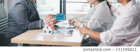 Panorama view of business meeting with miniature house model on desk, real estate contract signing, property investment, mortgage loan agreement and financial planning concept. mortgage loan agreement Panorama view of business meeting with miniature house model on desk, real estate contract signing, property investment, mortgage loan agreement and financial planning concept. mortgage loan agreement 131599021