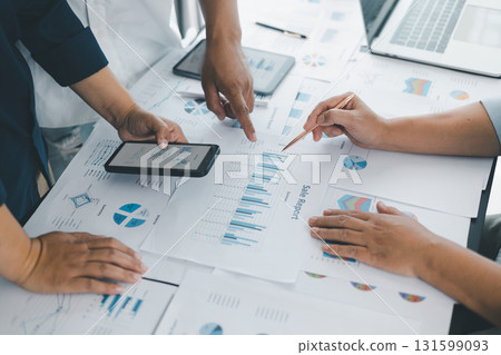 Business teamwork reviewing financial report with charts and graphs in modern office, colleagues discussing analysis, planning strategy, growth and corporate success with documents and technology. 131599093
