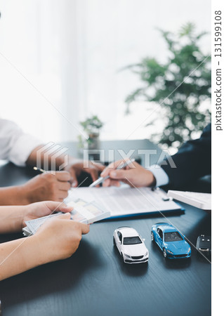 Businessman explaining car loan agreement with calculator, customer discussing auto finance deal at office desk with toy car and document, concept of vehicle loan, insurance or car leasing. car loan. Businessman explaining car loan agreement with calculator, customer discussing auto finance deal at office desk with toy car and document, concept of vehicle loan, insurance or car leasing. car loan. 131599108
