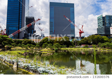 Flood control sandbags and construction cranes reflected in the pond at the former Shiba Rikyu Gardens in Tokyo, with skyscrapers Flood control sandbags and construction cranes reflected in the pond at the former Shiba Rikyu Gardens in Tokyo, with skyscrapers 131600376