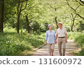 微笑的老年夫婦手牽手在公園散步，享受春天陽光和大自然的寧靜時光 131600972