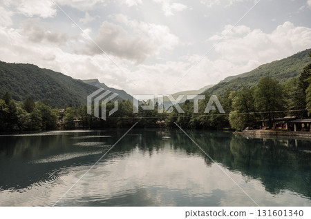 The mirror-like surface of a mountain lake, framed by dense green forests 131601340