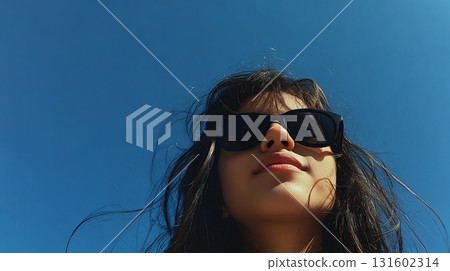 Portrait of a woman wearing sunglasses under a blue sky 131602314