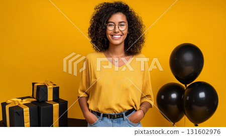 Happy satisfied smiling girl in 90s retro style on a yellow background with black balloons and black packages. Consumerism, sales, black friday. Online shopping. 131602976
