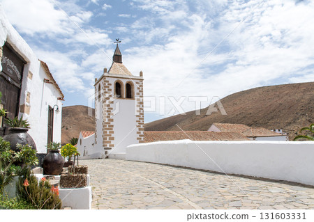 A historic church with white walls bathed in bright sunlight in Betancuria, inland on Fuerteventura in the Canary Islands. A historic church with white walls bathed in bright sunlight in Betancuria, inland on Fuerteventura in the Canary Islands. 131603331