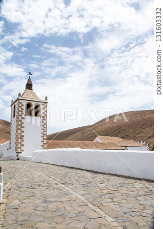 A historic church with white walls bathed in bright sunlight in Betancuria, inland on Fuerteventura in the Canary Islands. 131603332
