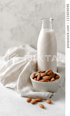 Homemade almond milk bottle and raw nuts isolated on white background, perfect for clean vegan lifestyle visuals. 131604046