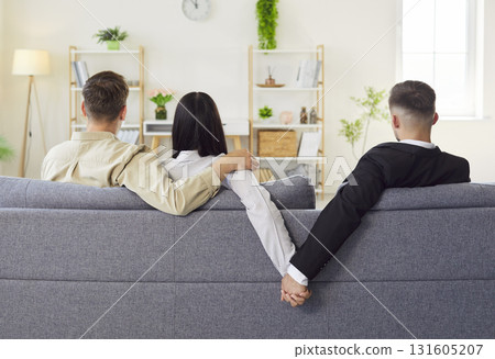 Back view of woman on sofa hugging lover while secretly holding another man hand Back view of woman on sofa hugging lover while secretly holding another man hand 131605207