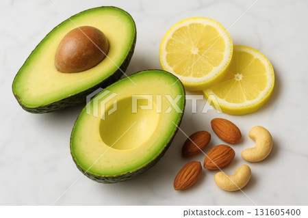 Fresh halved avocados with lemon slices, almonds & cashews on marble 131605400