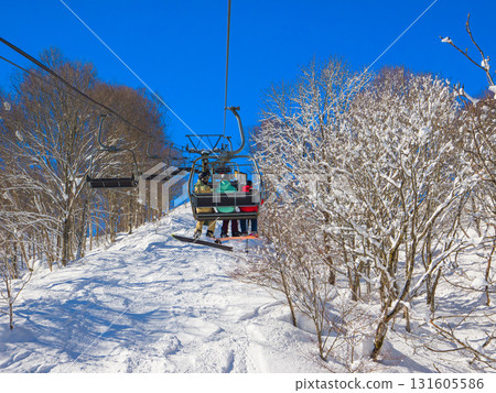 A ski lift ascending through a snow-covered forest at a ski resort on a clear day (Madarao Plateau, Niigata Prefecture) A ski lift ascending through a snow-covered forest at a ski resort on a clear day (Madarao Plateau, Niigata Prefecture) 131605586