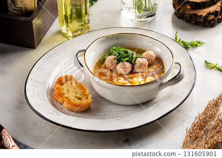 Soup with mini meatballs and pasta in bowl 131605901