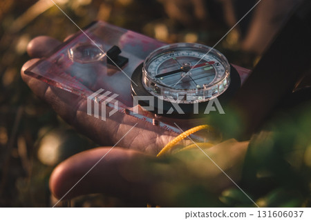man holding compass in forest during sunny day while exploring natural surroundings. closeup. man holding compass in forest during sunny day while exploring natural surroundings. closeup. 131606037
