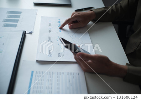 Professional businessman, entrepreneur or accountant working on a financial report paperwork at his desk, using mobile phone. 131606124