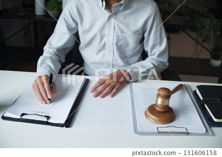 Legal justice man working on desk reading supportive documents to determine the case Legal justice man working on desk reading supportive documents to determine the case 131606158