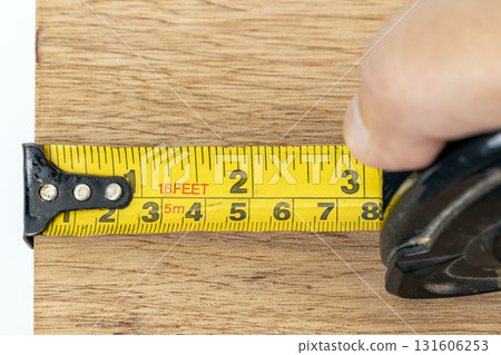 Tape measure measuring tape carpenter hand wood measurement workshop construction accuracy tool with calm focus as precise measurement enhances craft Tape measure measuring tape carpenter hand wood measurement workshop construction accuracy tool with calm focus as precise measurement enhances craft 131606253