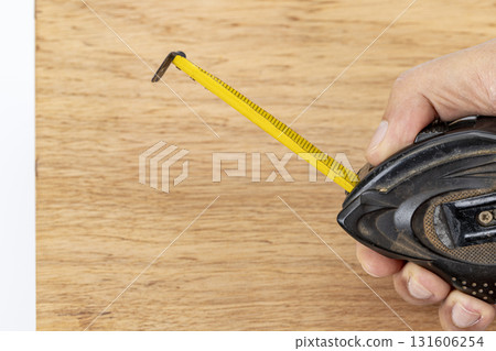 Measuring tape yellow tape wood surface hand tool construction carpentry DIY workshop precision measuring tape extends across wood with hand holding tool, careful carpentry and DIY work evoke Measuring tape yellow tape wood surface hand tool construction carpentry DIY workshop precision measuring tape extends across wood with hand holding tool, careful carpentry and DIY work evoke 131606254