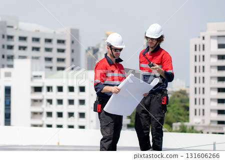 Two engineer checking solar energy system looking blueprint together. 131606266