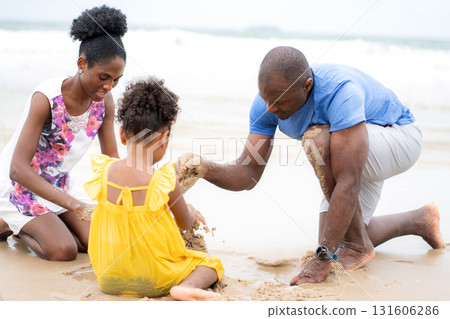 Happy black family sitting playing sand on beach together for leisure during summer vacation. Happy black family sitting playing sand on beach together for leisure during summer vacation. 131606286
