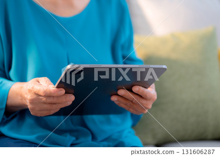 Close up hand senior woman reading tablet in living room at home. 131606287