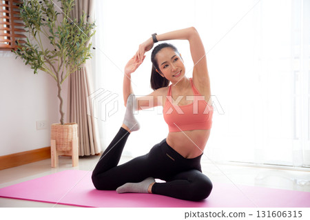 Young asian woman practicing Yoga with stretching muscle back on yoga mat in living room. Young asian woman practicing Yoga with stretching muscle back on yoga mat in living room. 131606315
